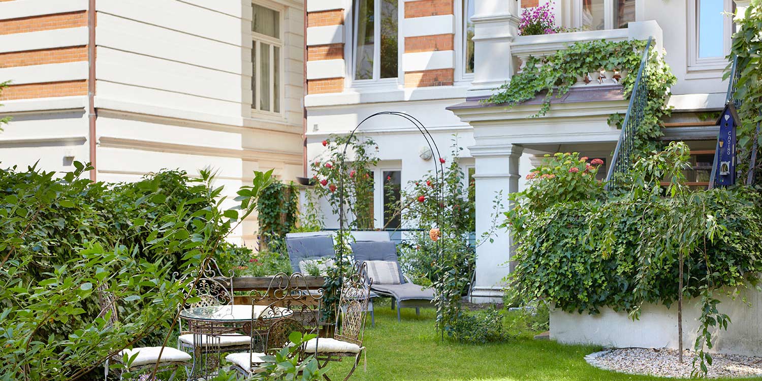 Gartenseite des Hotel am Museum mit begrünter Fassade und Sitzplätzen im Hotelgarten